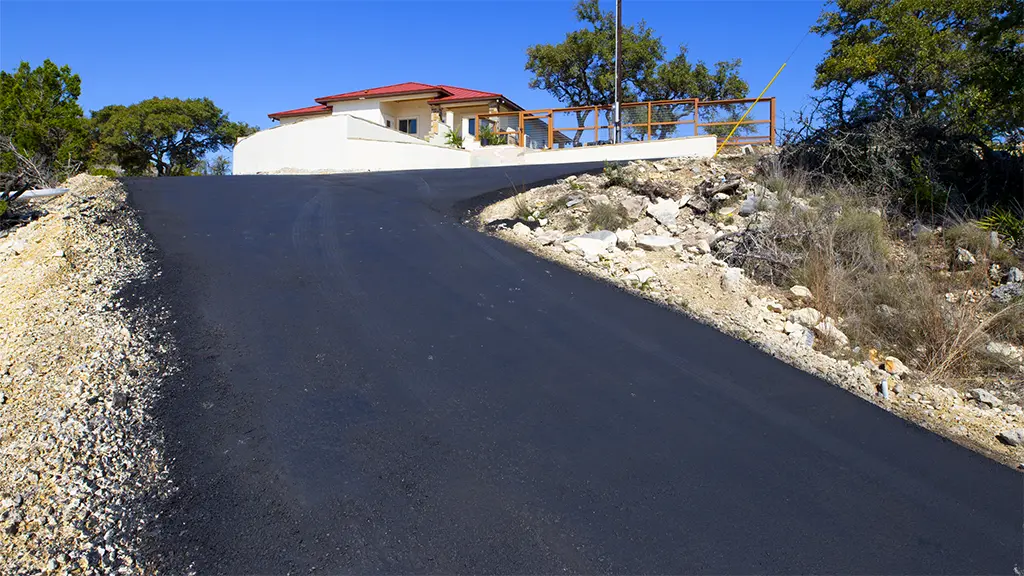 A newly paved residential asphalt driveway in the hill country